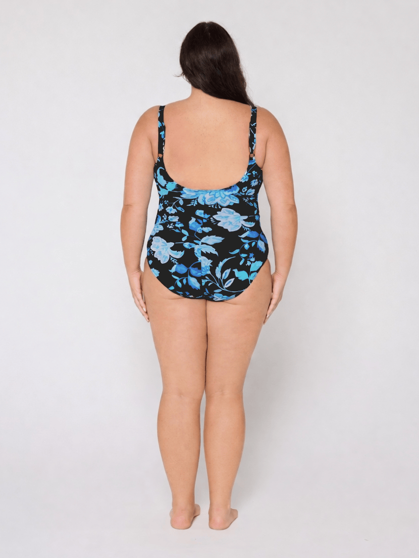 Woman wearing a blue and black floral swimsuit with scoop back