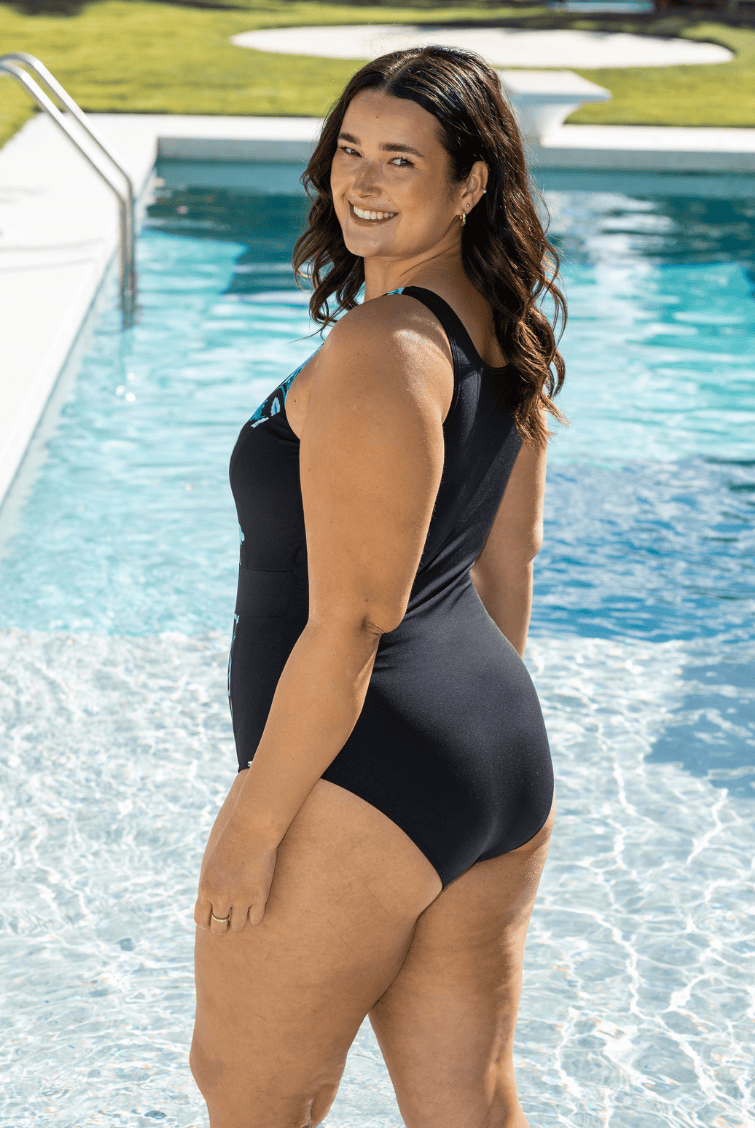 Woman in a blue and black swimsuit with high back standing in a pool