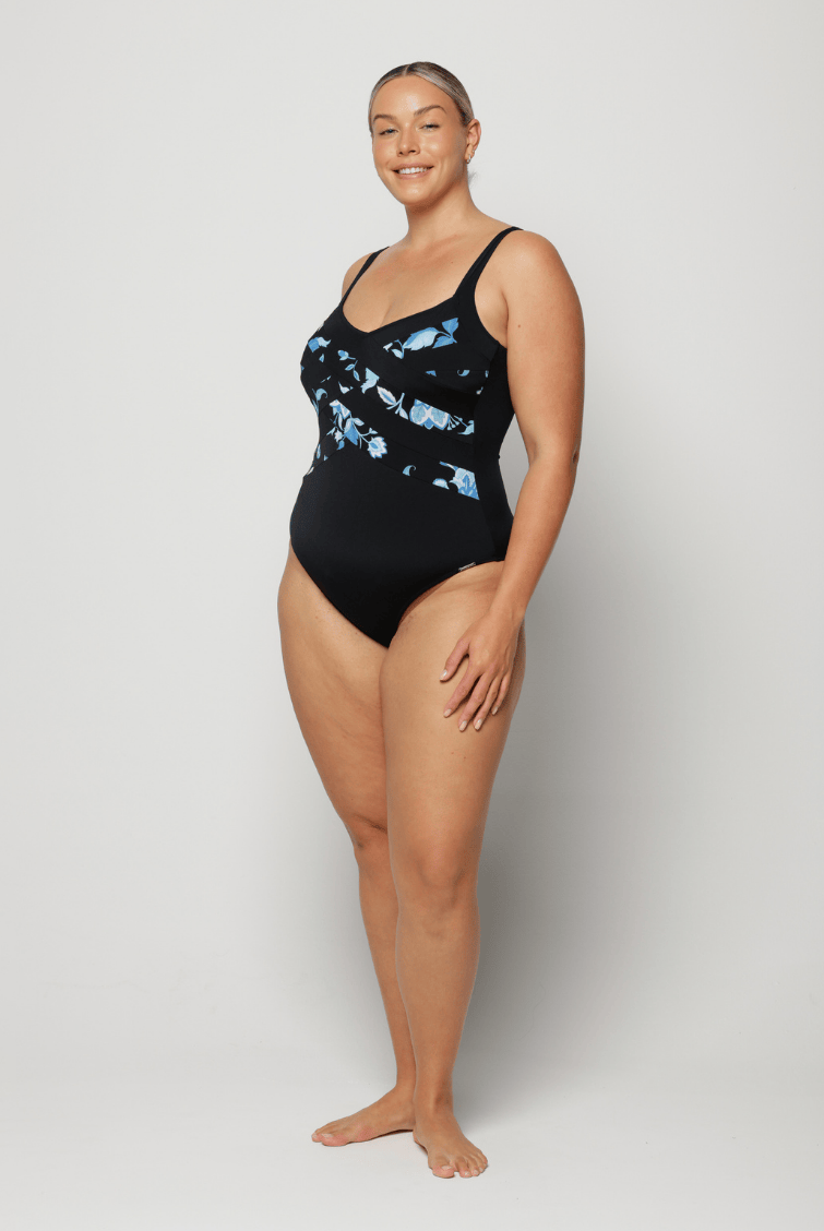 Woman wearing a black swimsuit with blue floral pattern on a white background