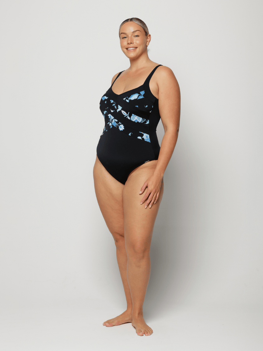 Woman wearing a black swimsuit with blue floral pattern on a white background