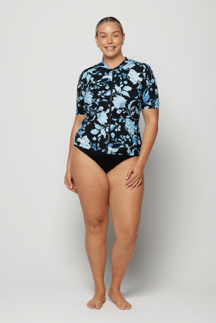 Woman wearing a black floral short sleeve rash vest in chlorine resistant