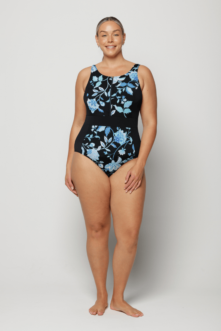 Woman wearing a black one-piece swimsuit with blue floral patterns on a white background
