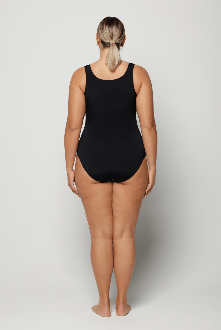 Person wearing a black and blue floral swimsuit against a white background