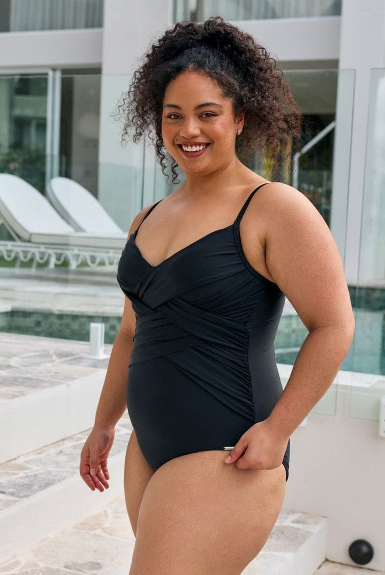 Side profile of model wearing a criss cross one piece with adjustable straps for curvy women