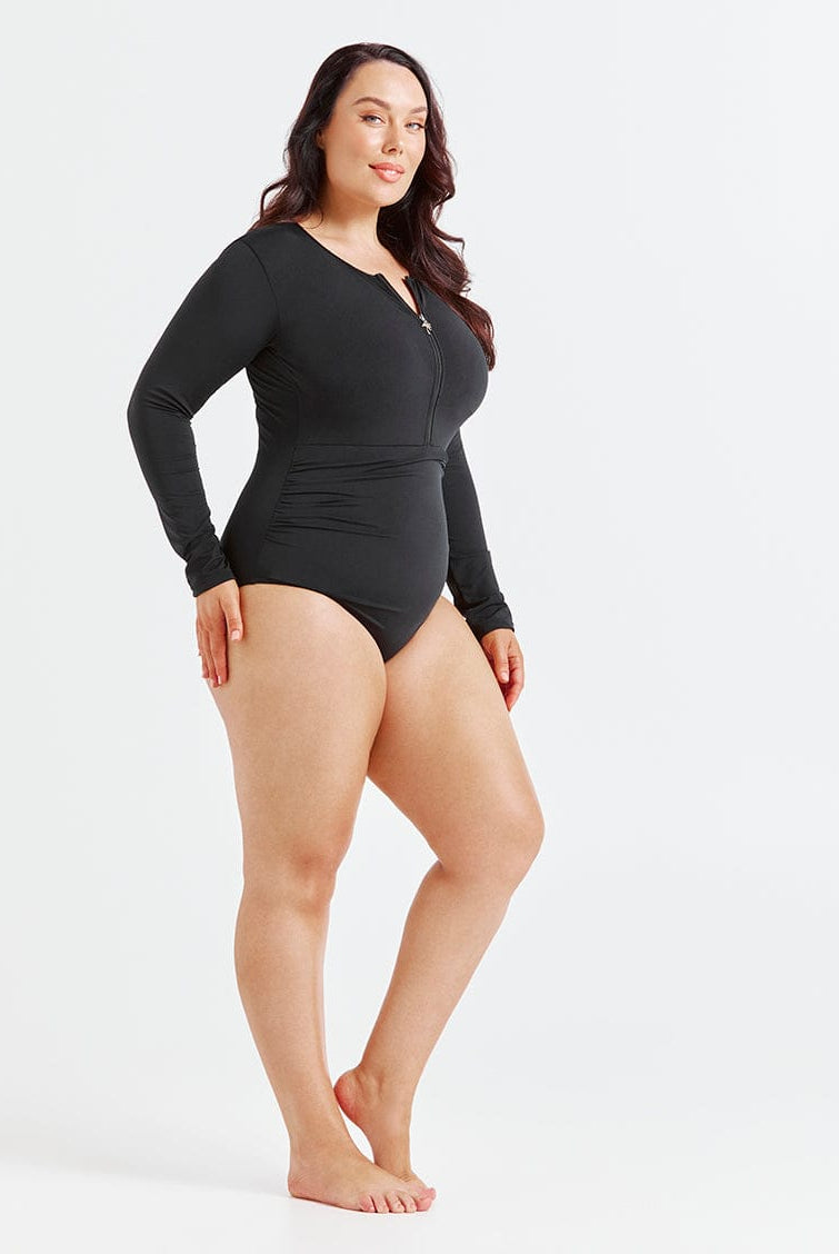 Woman wearing a black long-sleeve swimsuit on a white background