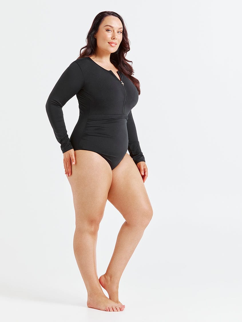 Woman wearing a black long-sleeve swimsuit on a white background