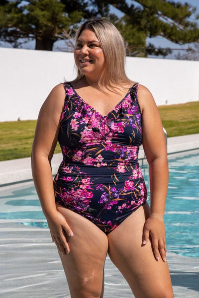 Curvy women wearing v neck one piece with frill detail neckline in pink and purple floral tones
