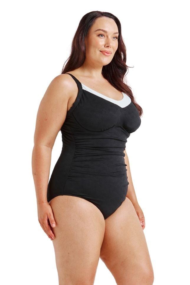Brunette model showing side of black and white womens one piece