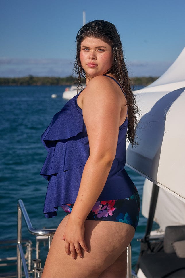 Plus size model wearing ruffle swim top in metallic navy