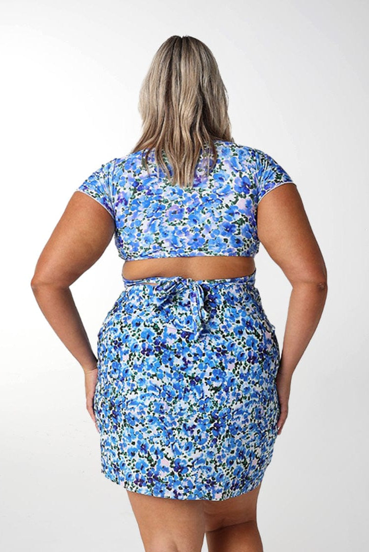Back of model wearing floral blue mini skirt with tie detail