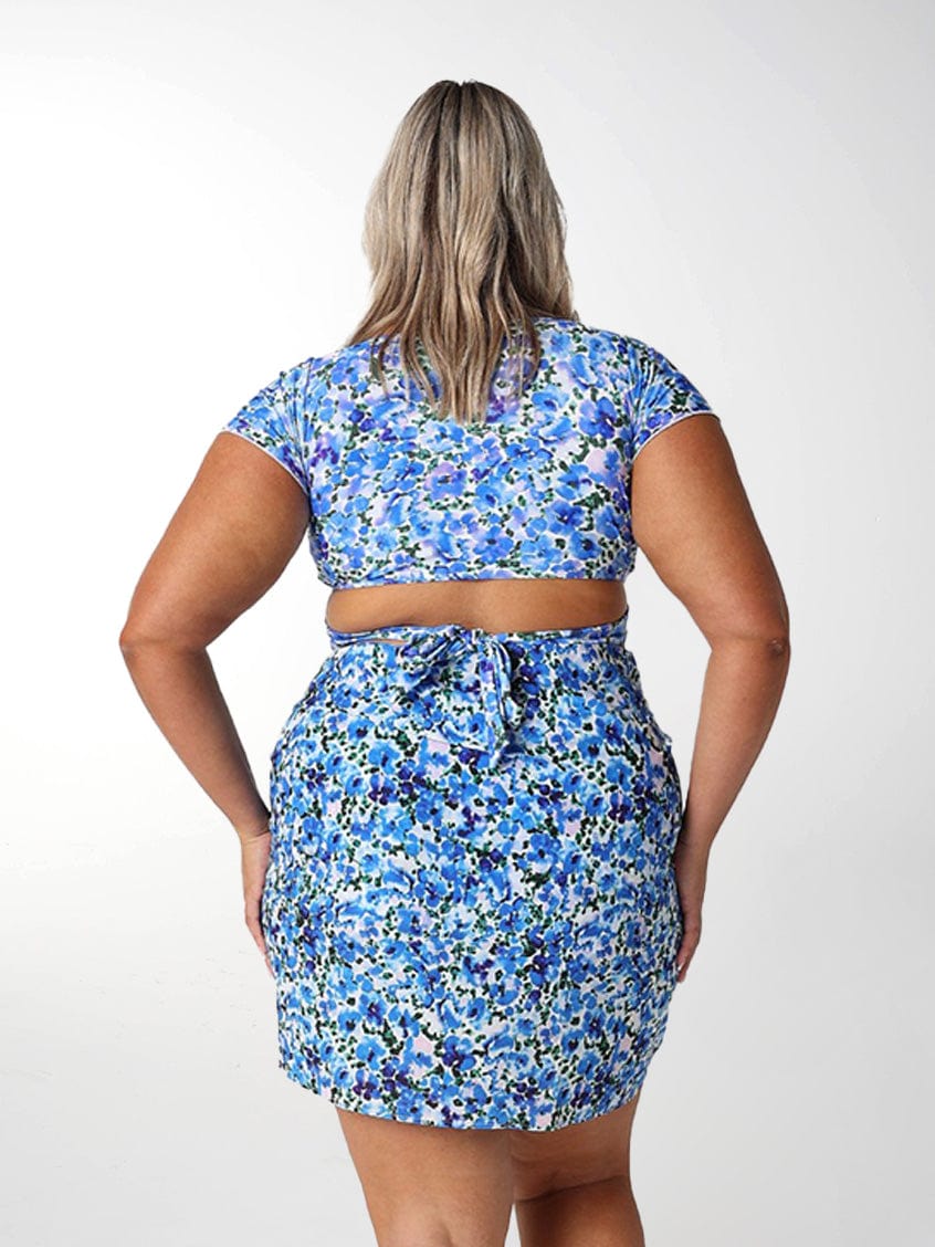 Back of model wearing floral blue mini skirt with tie detail