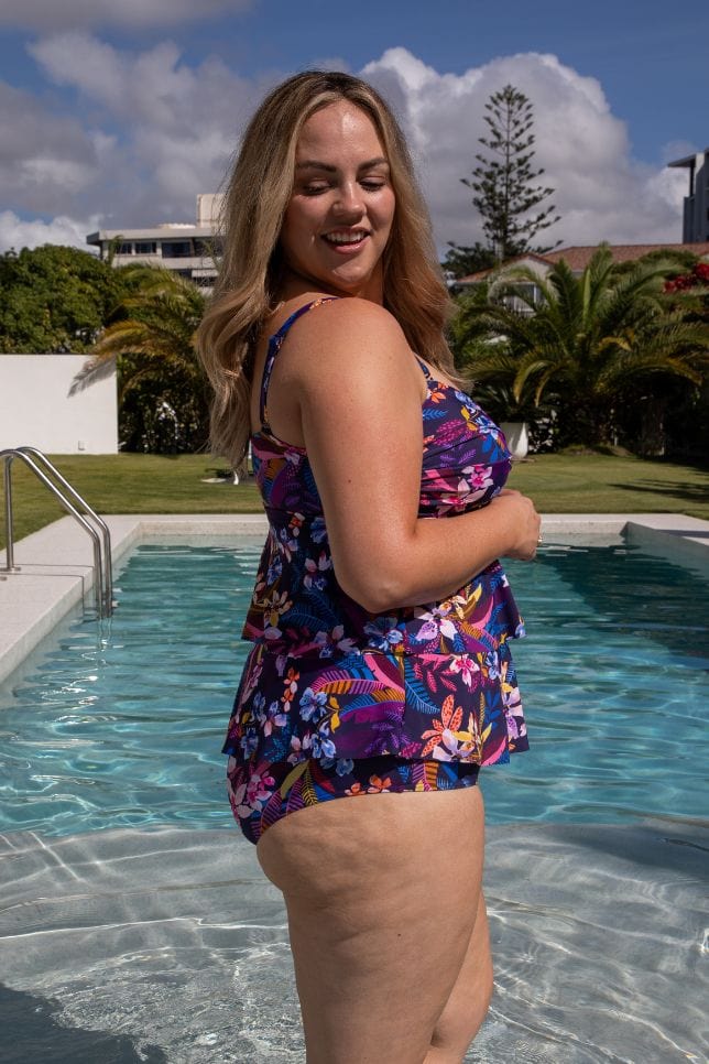 Side profile of model in pool wearing a navy based floral tankini top for curve women