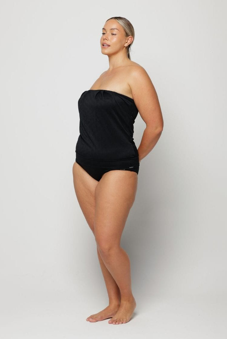 Woman wearing a black strapless swimsuit against a white background