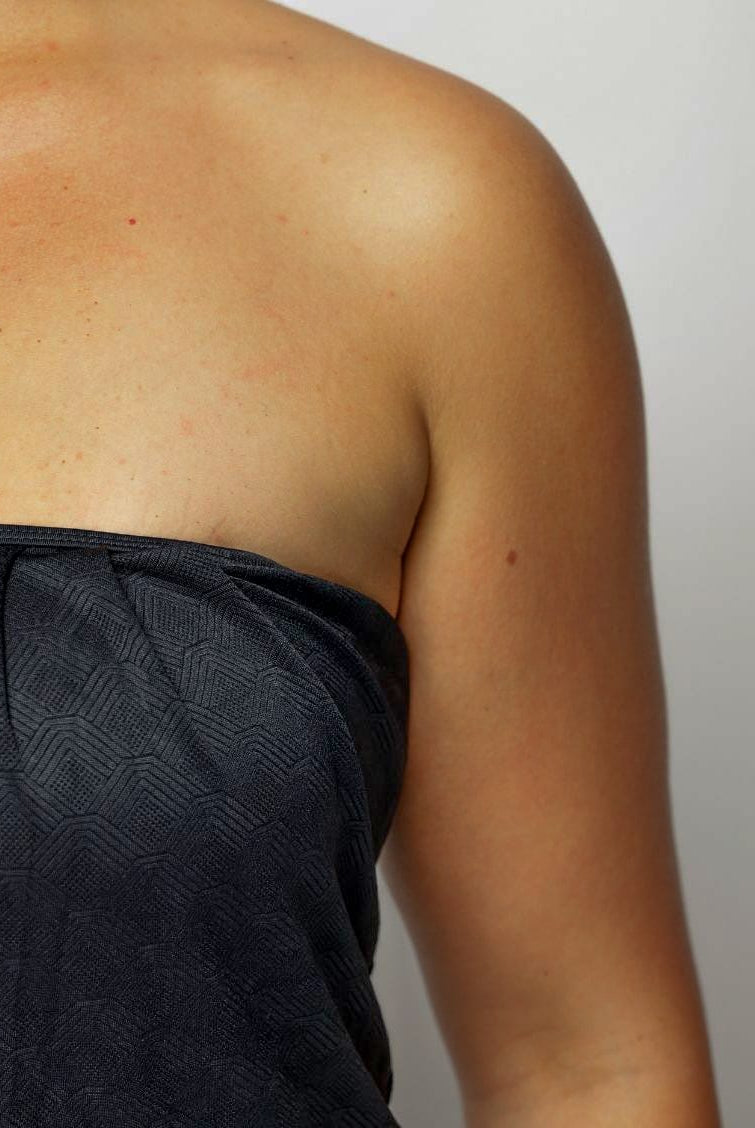 Close up of a Women wearing a strapless black swimsuit against a plain background