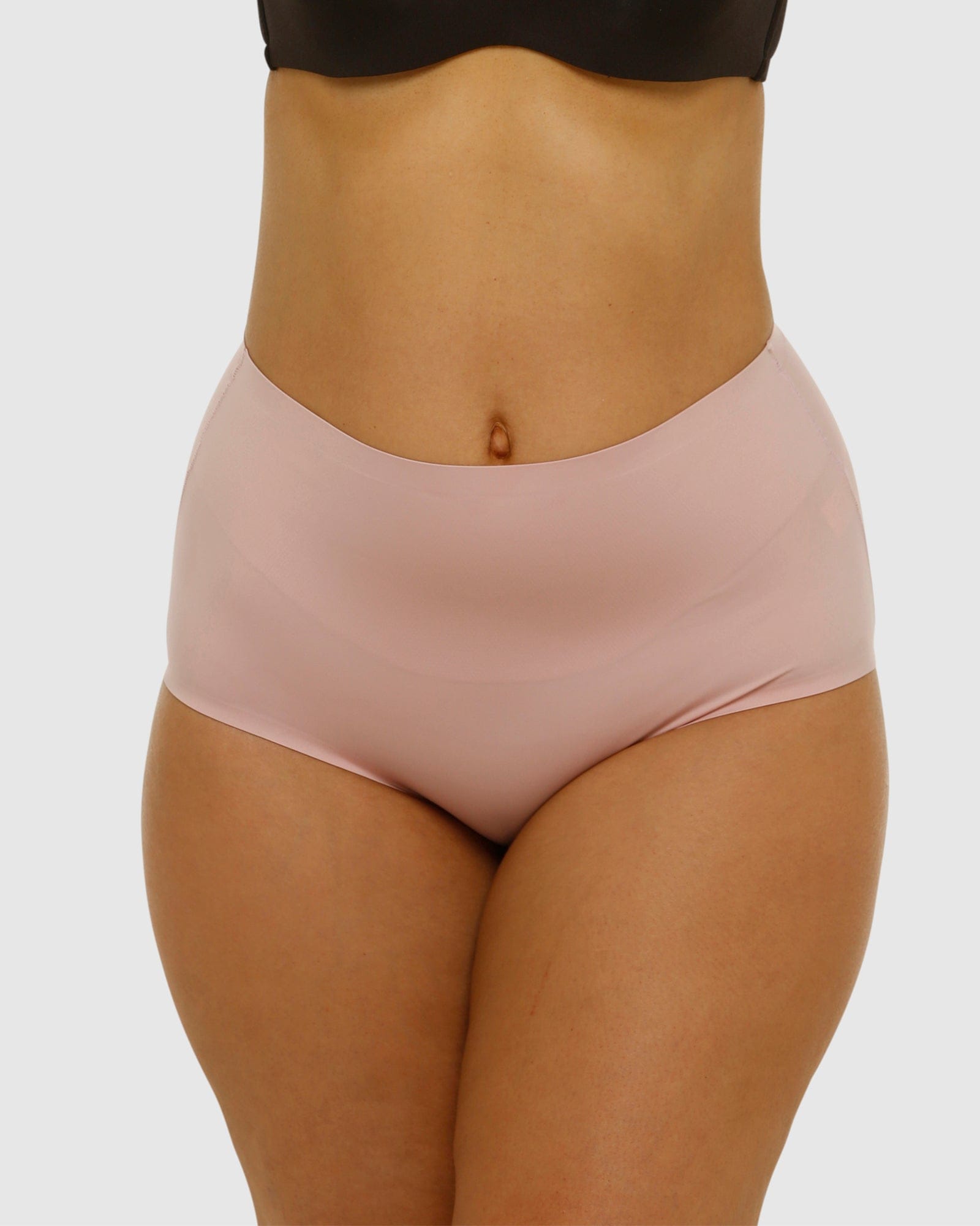 Person wearing light pink high-waisted underwear on a white background