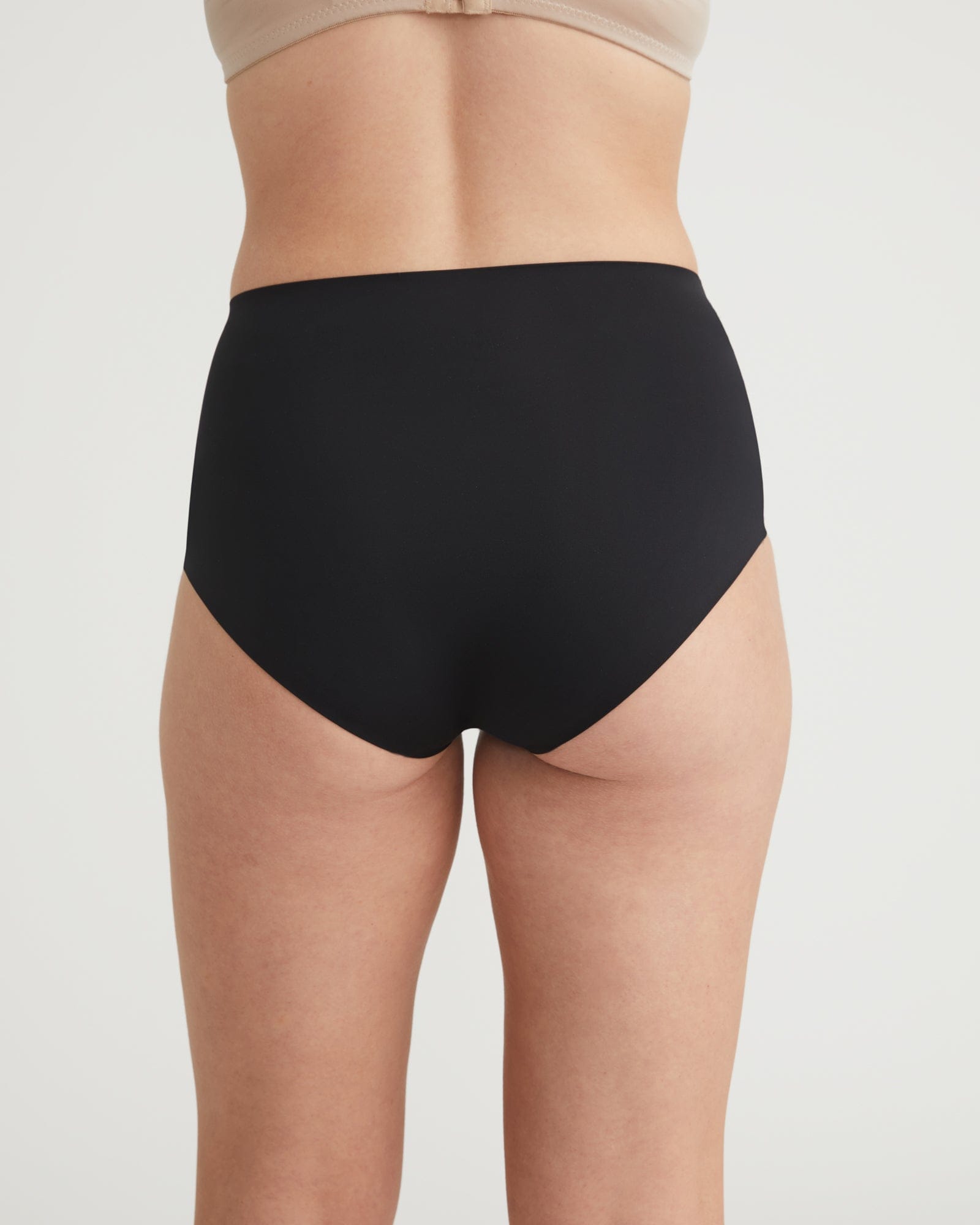 Black high-waisted underwear worn by a person on a light gray background