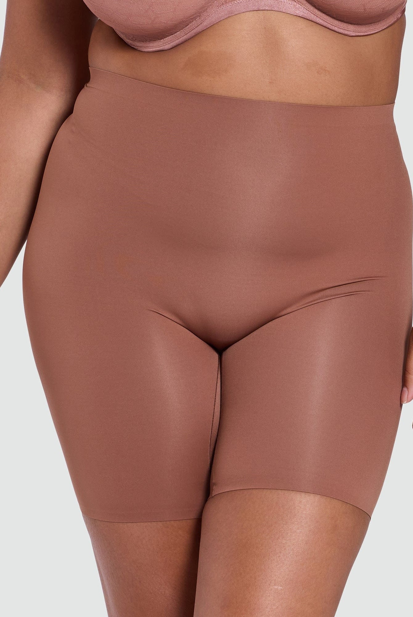 Brown high-waisted shorts worn by a person on a light gray background