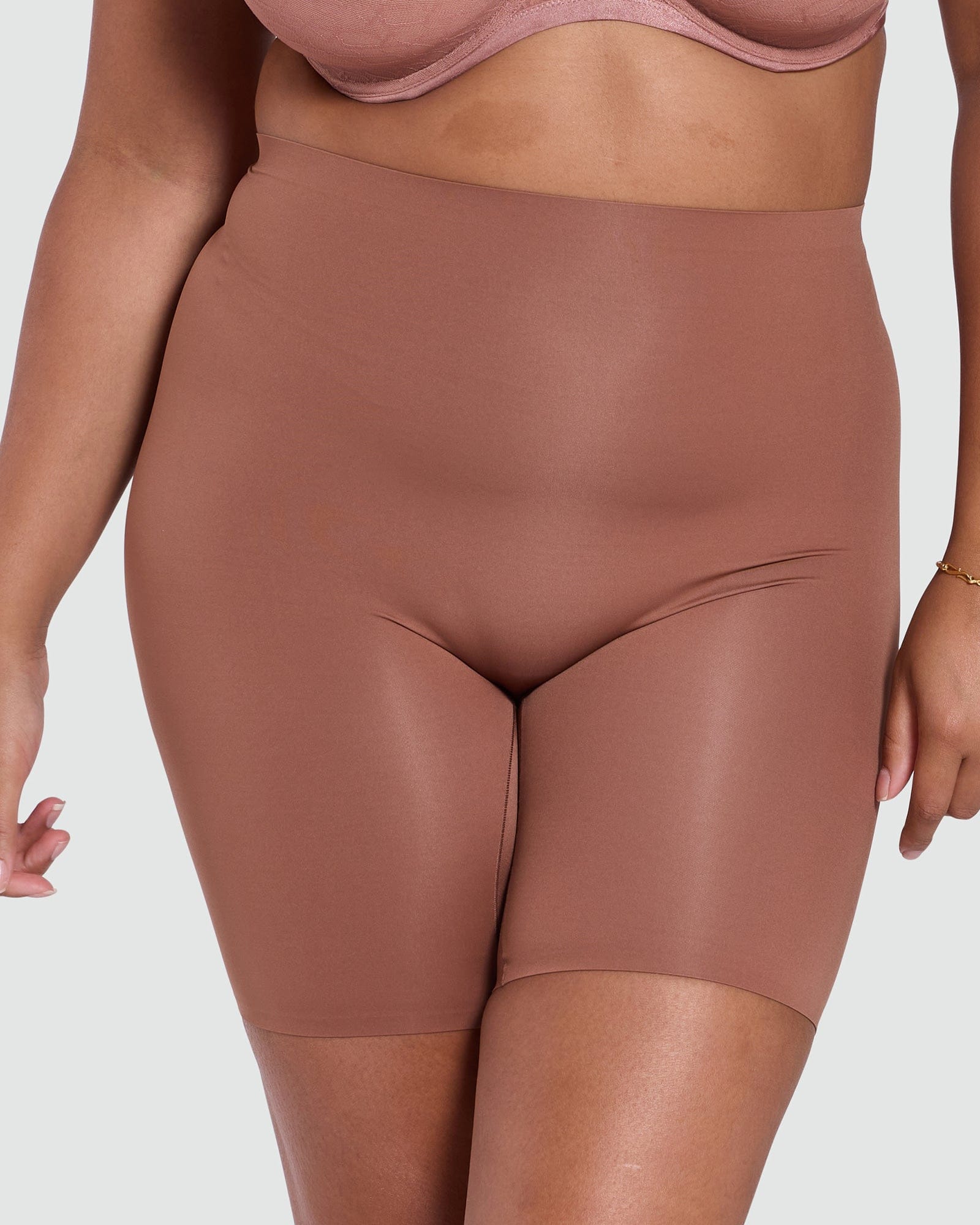 Brown high-waisted shorts worn by a person on a light gray background