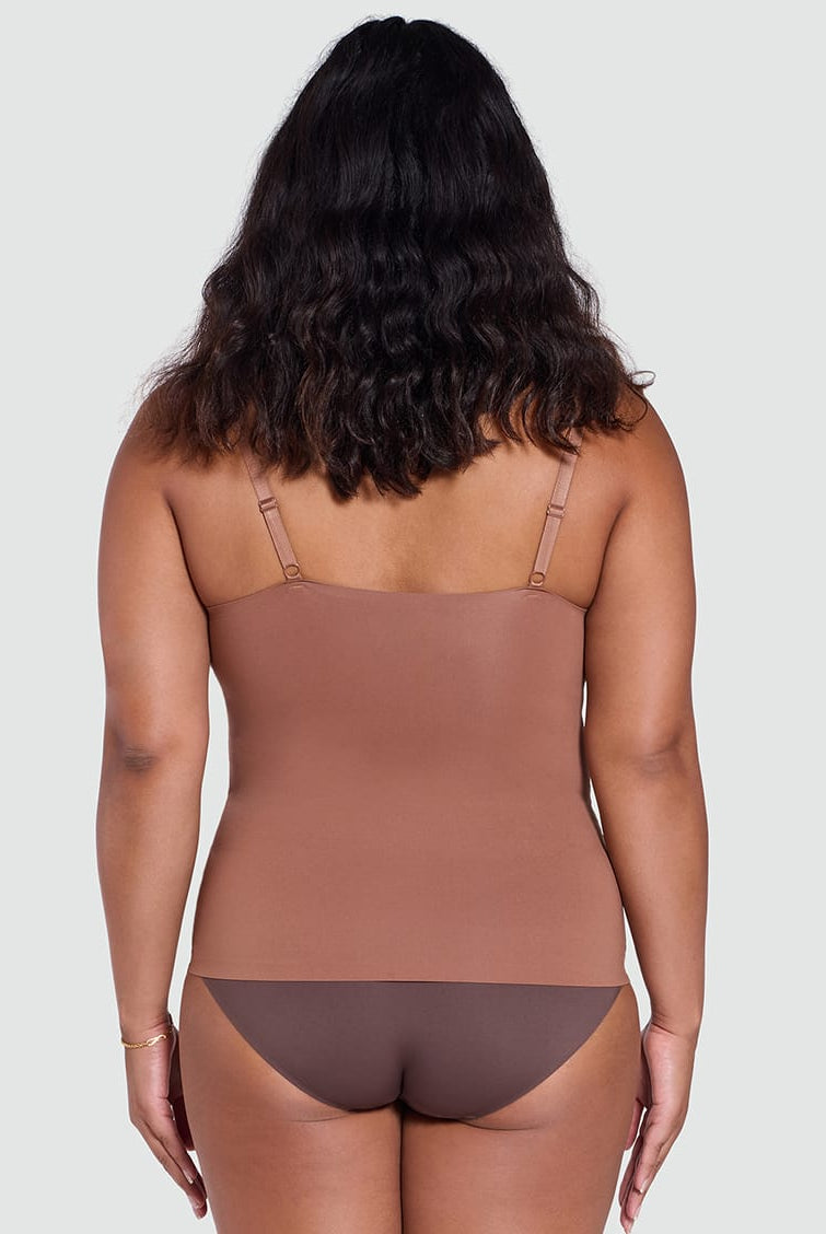 Woman wearing a brown bodysuit against a plain background