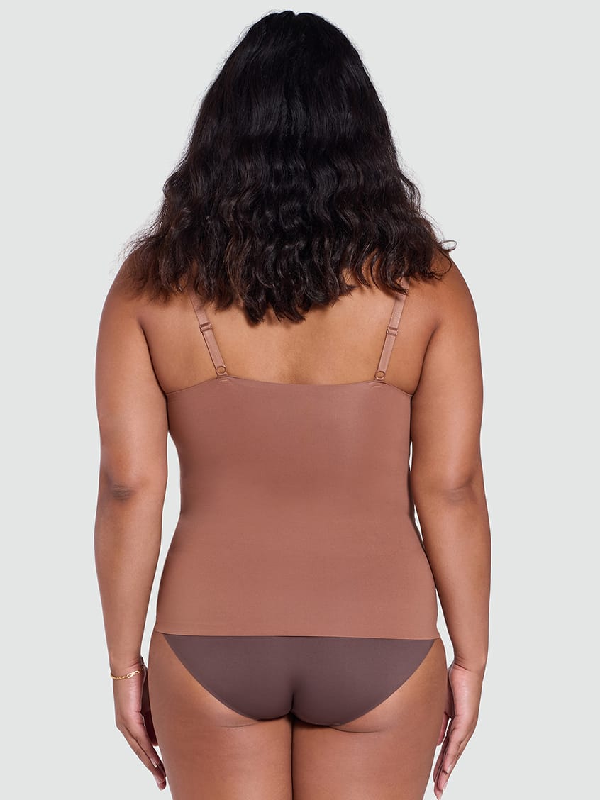 Woman wearing a brown bodysuit against a plain background