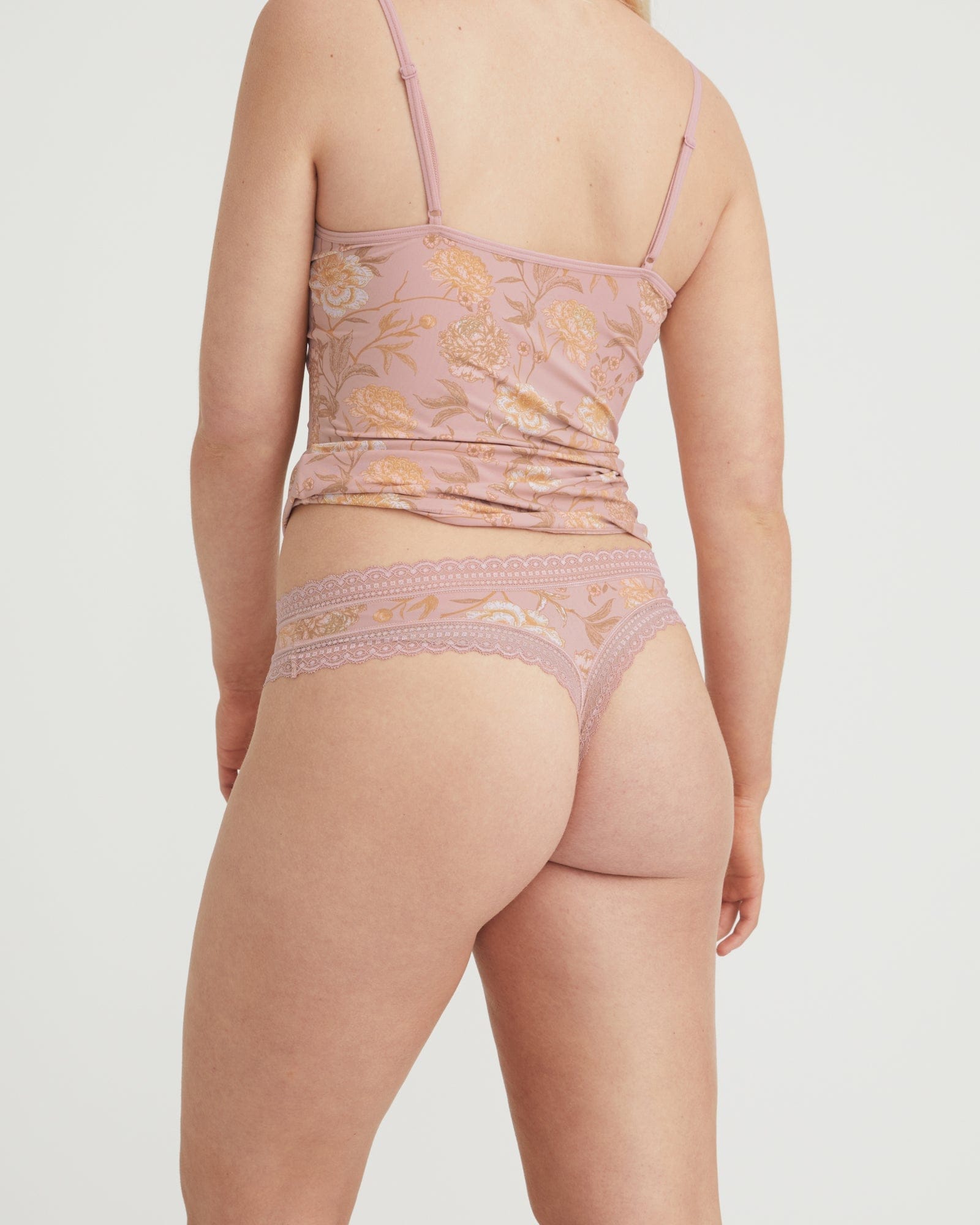 Person wearing a pink lace lingerie set on a plain background