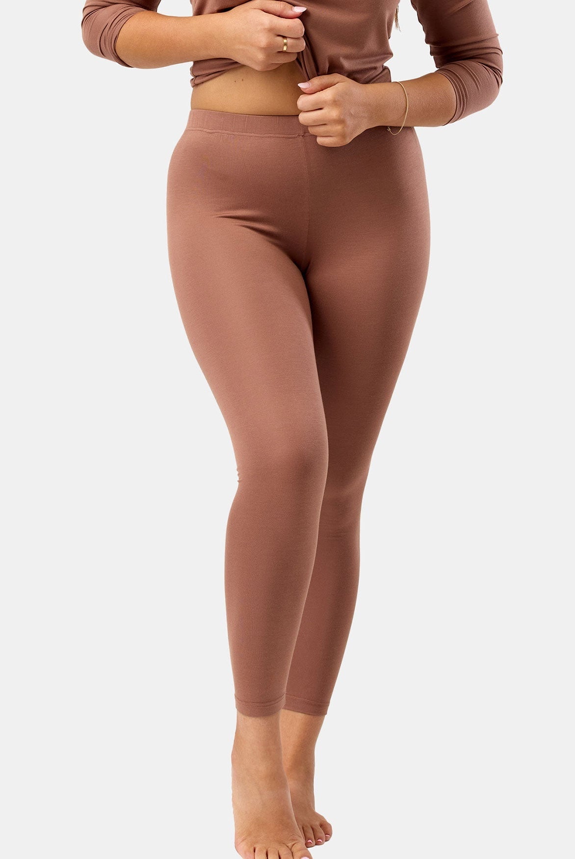Person wearing brown leggings and top on a white background