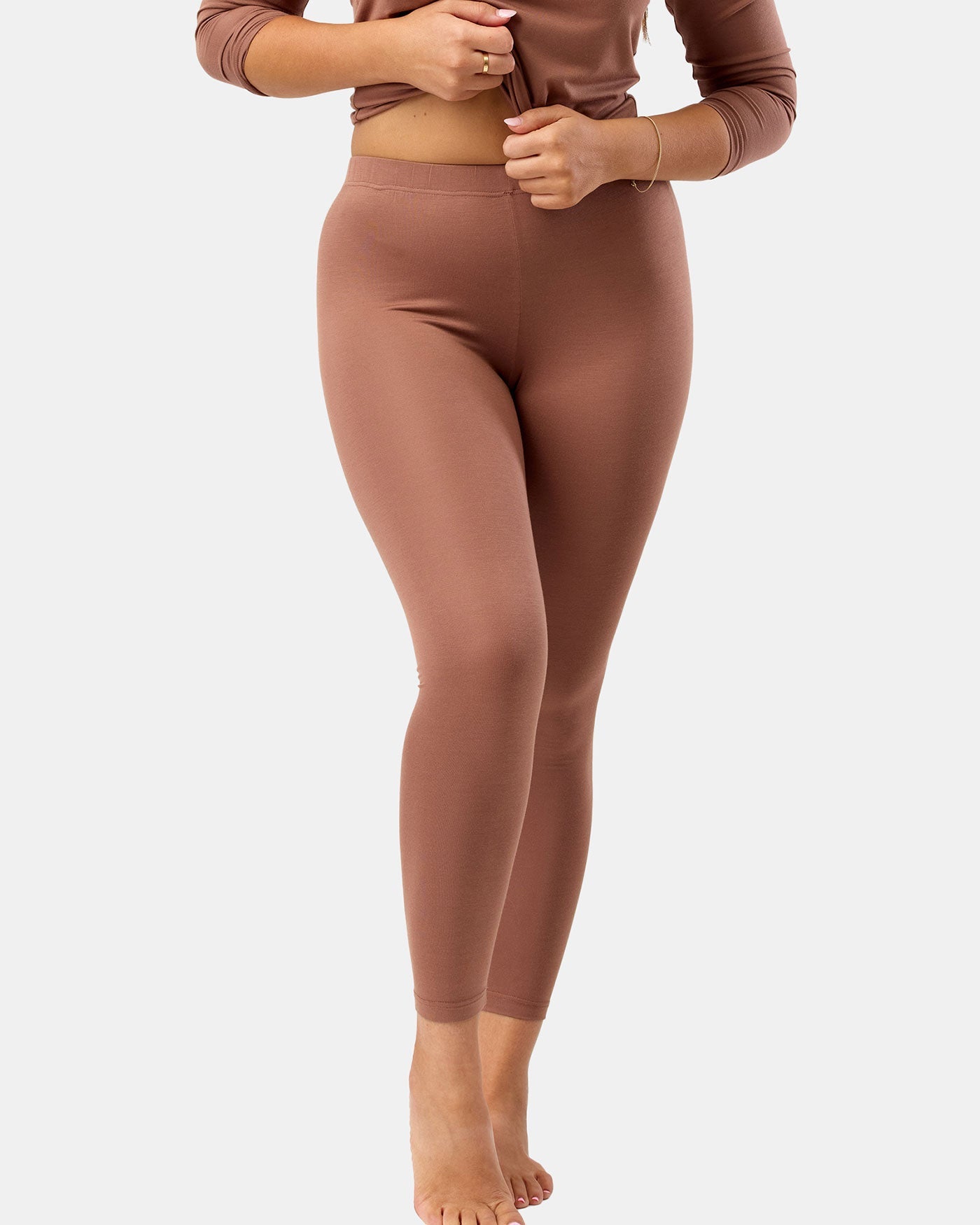 Person wearing brown leggings and top on a white background