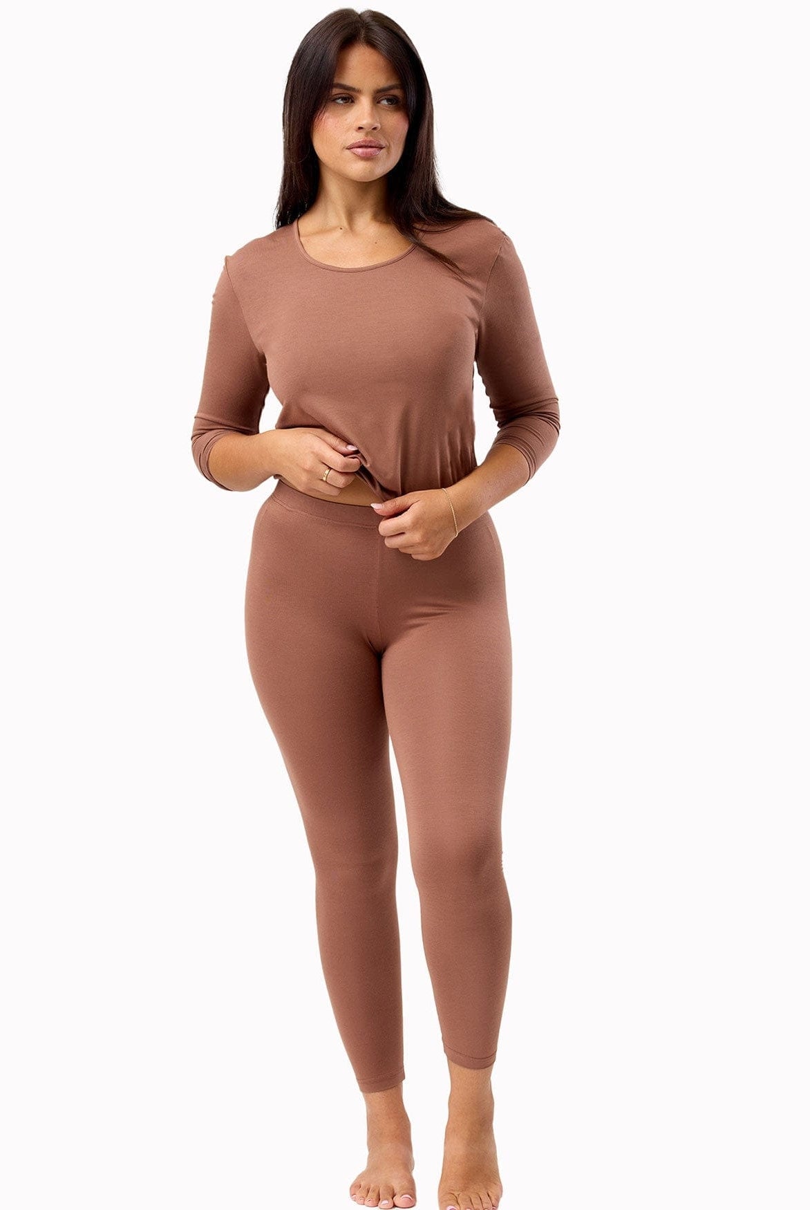 Woman wearing a brown long-sleeve top and leggings on a white background