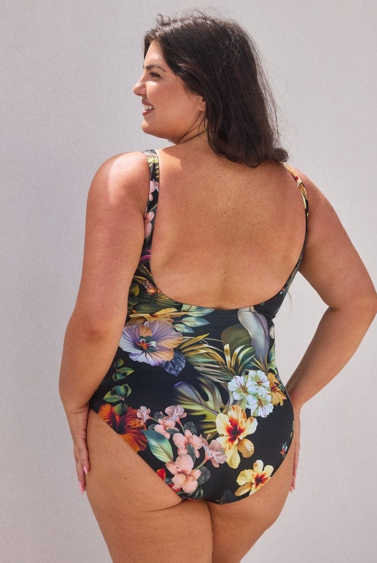 Woman wearing a floral one-piece swimsuit against a plain background