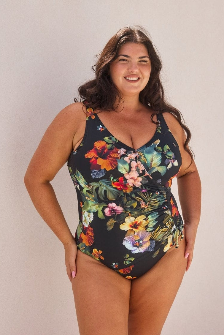 Woman wearing a floral one-piece swimsuit against a plain background