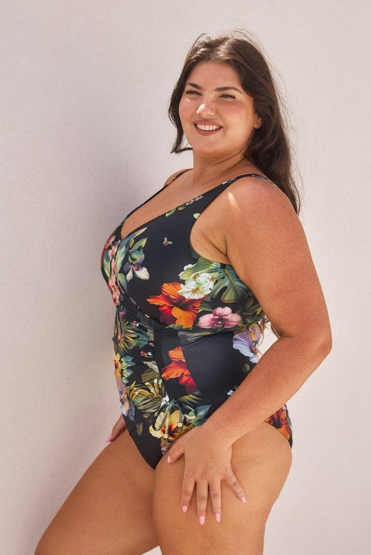Woman wearing a floral one-piece swimsuit against a plain background