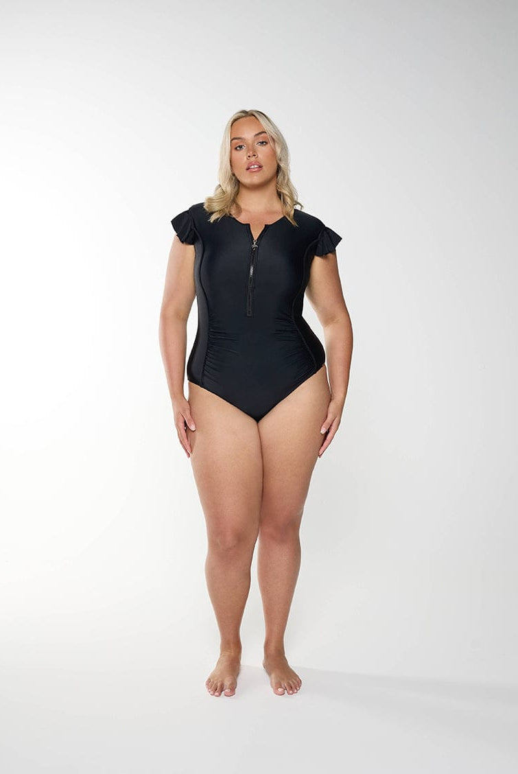 Person wearing a black swimsuit with cap sleeves on a white background