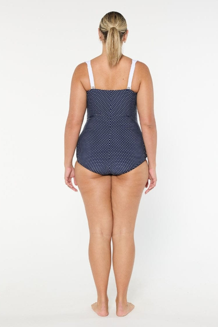 Woman wearing a navy polka dot swimsuit on a white background