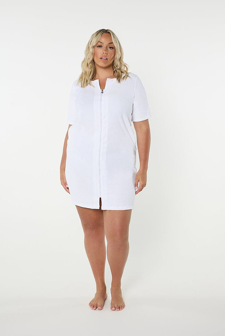 Woman wearing a white zip-up beach
dress on a plain background