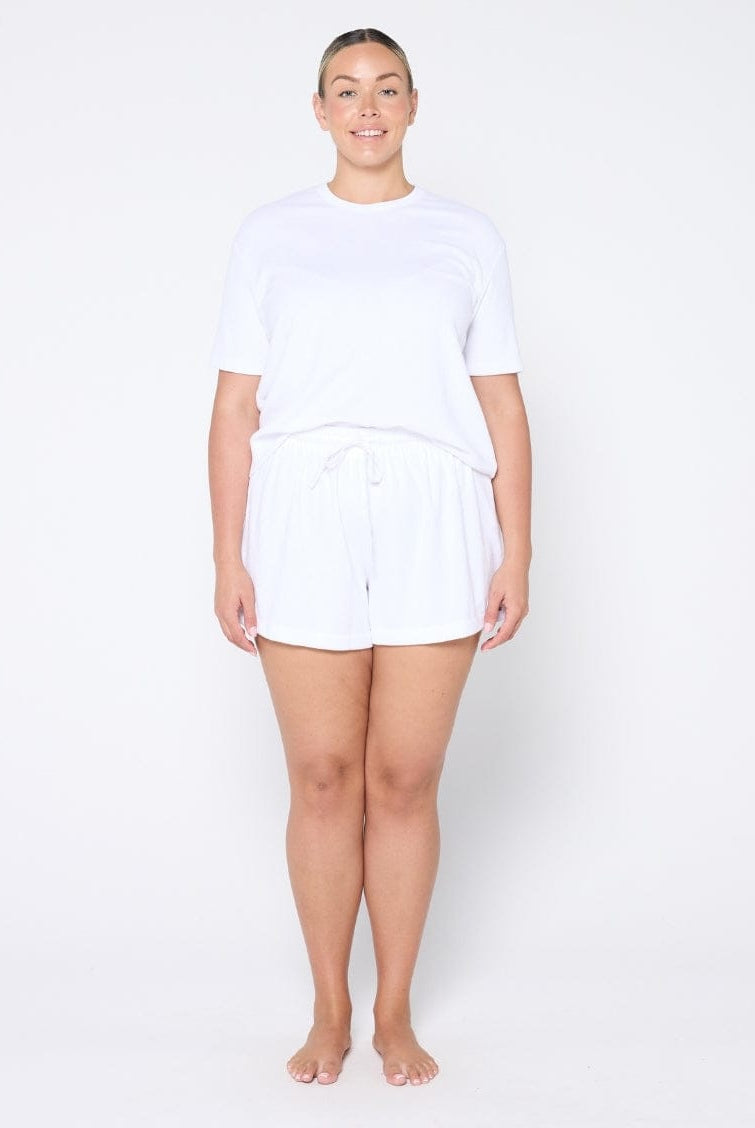 Person wearing a white t-shirt and shorts set on a plain background