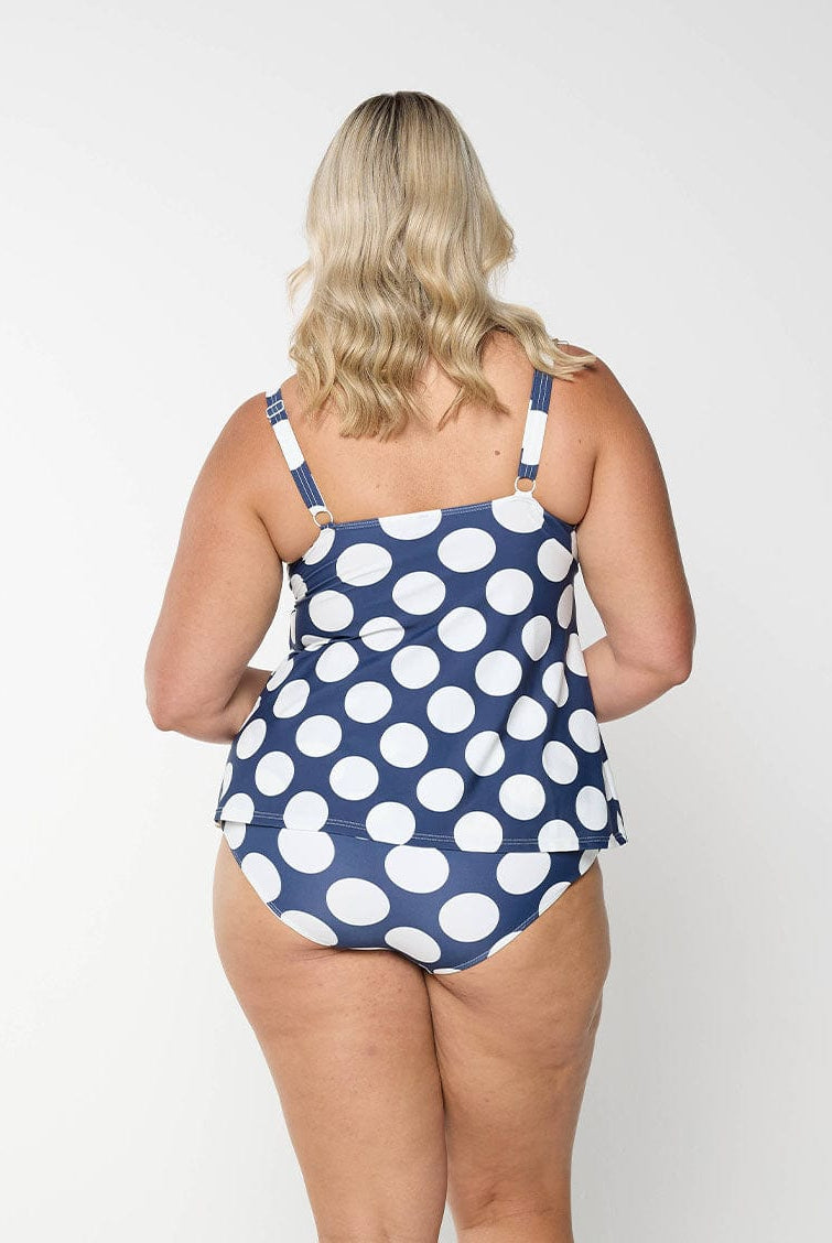 Plus size model shows the back of navy dot tankini top with adjustable straps