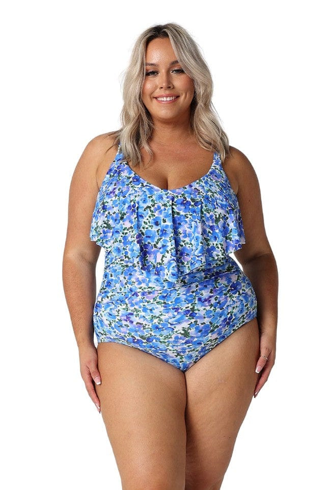 Blonde model in studio wearing curvy white and blue floral swimsuit with frill v neck
