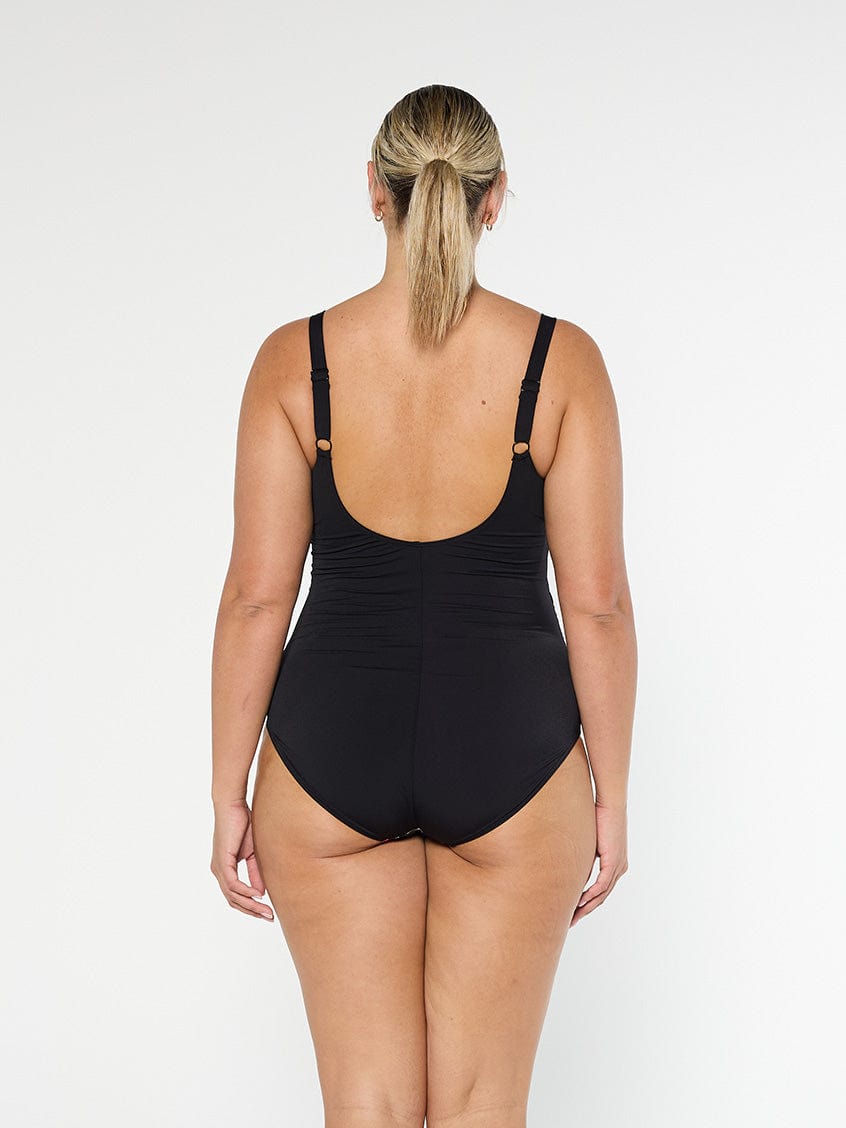 Blonde model shows low back one piece swimsuit in black chlorine resistant fabric