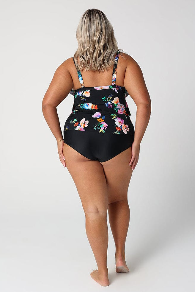 Woman wearing a black floral one-piece swimsuit on a white background
