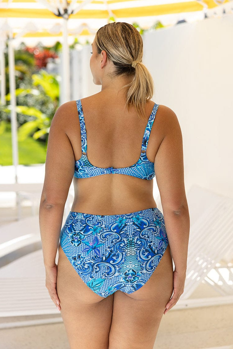 Woman wearing a blue patterned bikini set with a blurred outdoor background