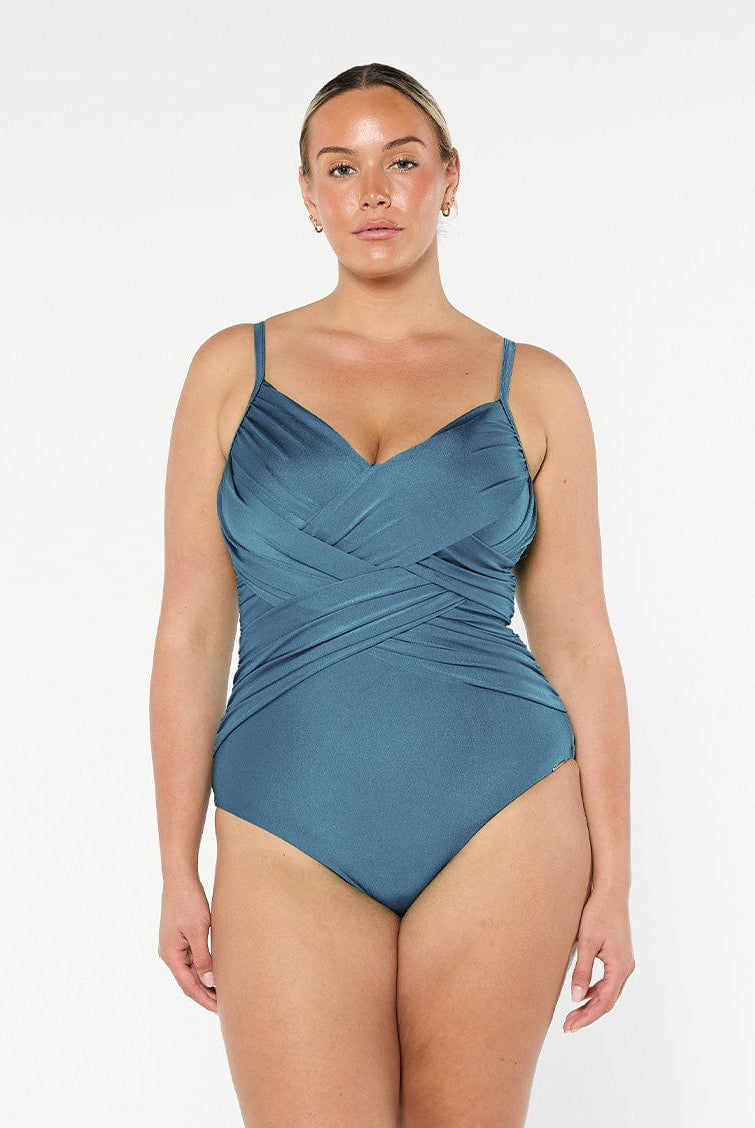 Blonde model in studio wearing a criss cross one piece with ruching and adjustable straps in metallic grey