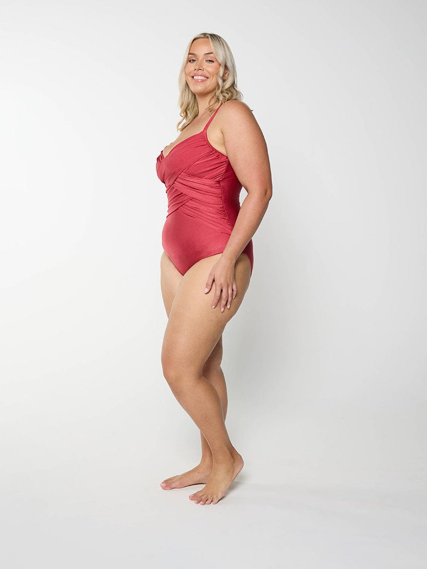Woman wearing a deep red swimsuit against a white background