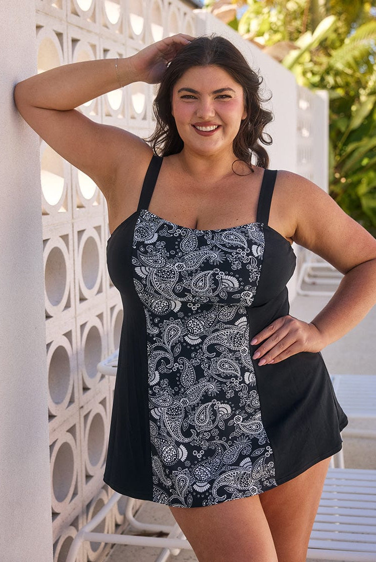 Brunette woman by pool wearing a chlorine resistant paisley swim dress with wide strap adjustable straps