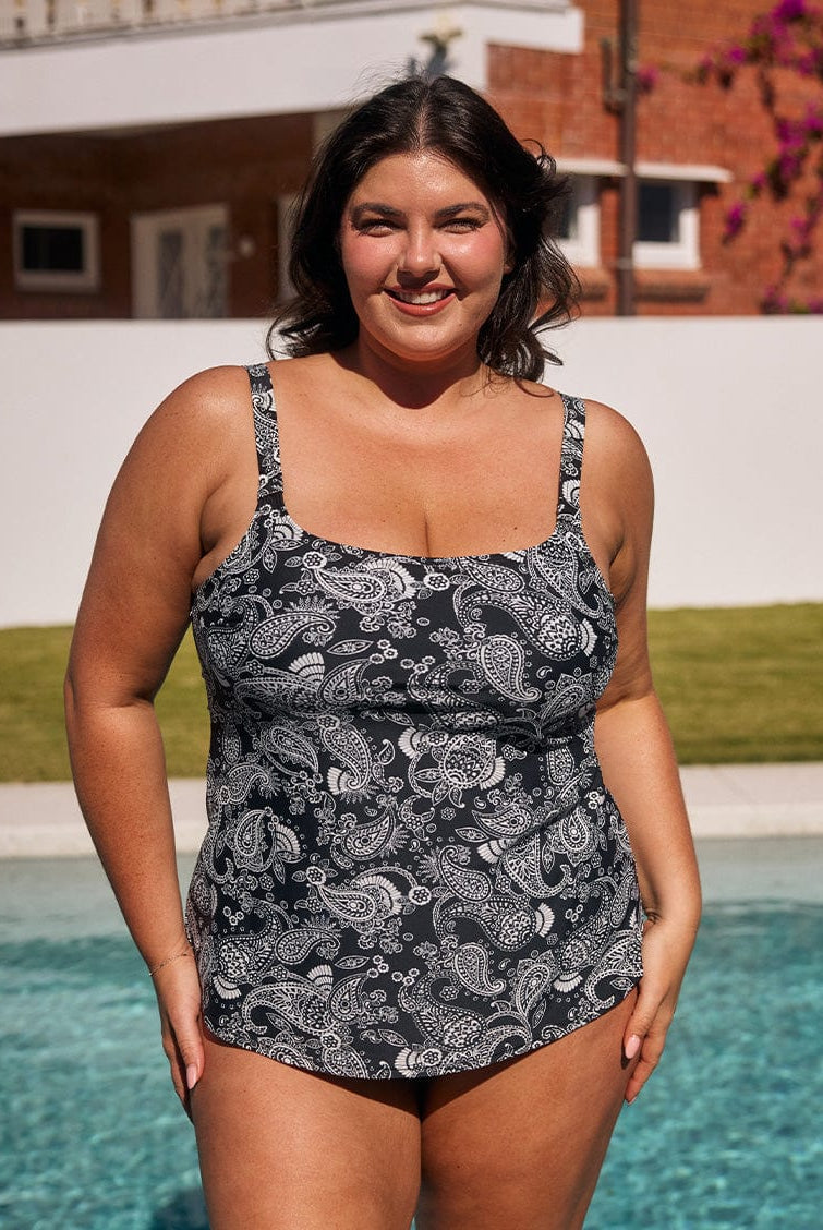 Brunette model standing by pool wearing a chlorine resistant tank tankini top with thick adjustable straps
