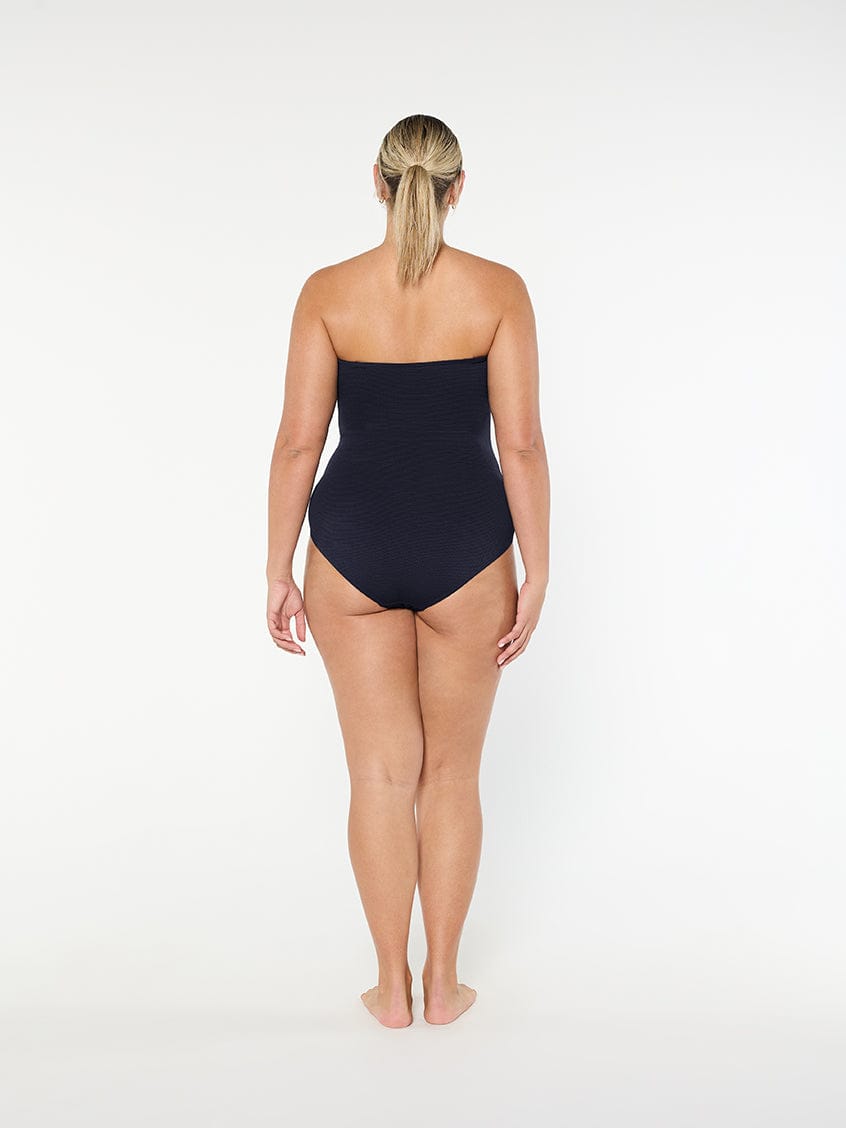 Woman wearing a black strapless swimsuit on a white background