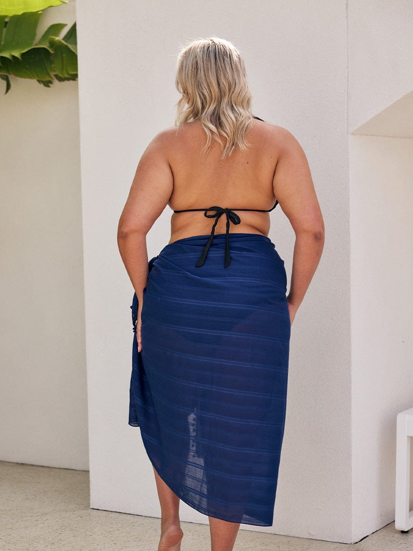 Back of curve model wearing a cotton sarong with pom poms and side details
