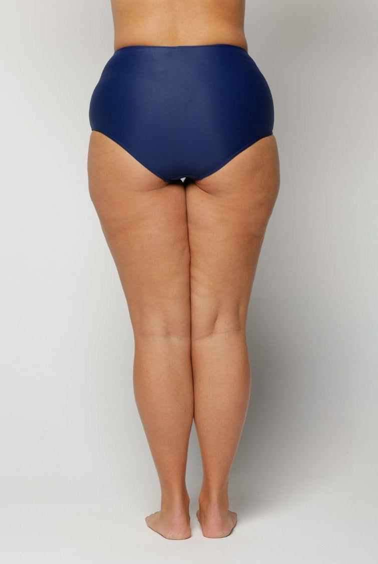 a woman wearing a Navy blue high-waisted swimsuit on a plain background