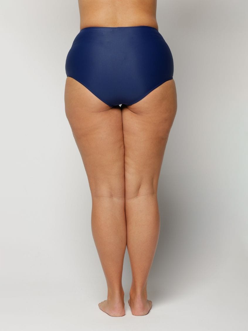 a woman wearing a Navy blue high-waisted swimsuit on a plain background