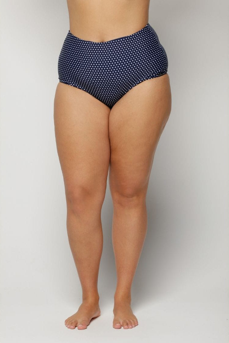 Woman wearing navy high-waisted bikini bottoms with a subtle pattern on a plain background