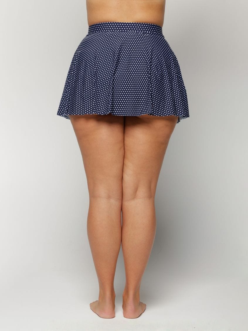 Navy polka dot skirt worn by a woman on a white background